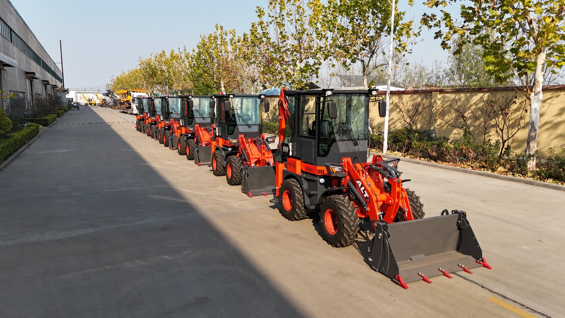 Line of backhoe loaders parked outside the AOLITE Heavy Industry factory, viewed from the side