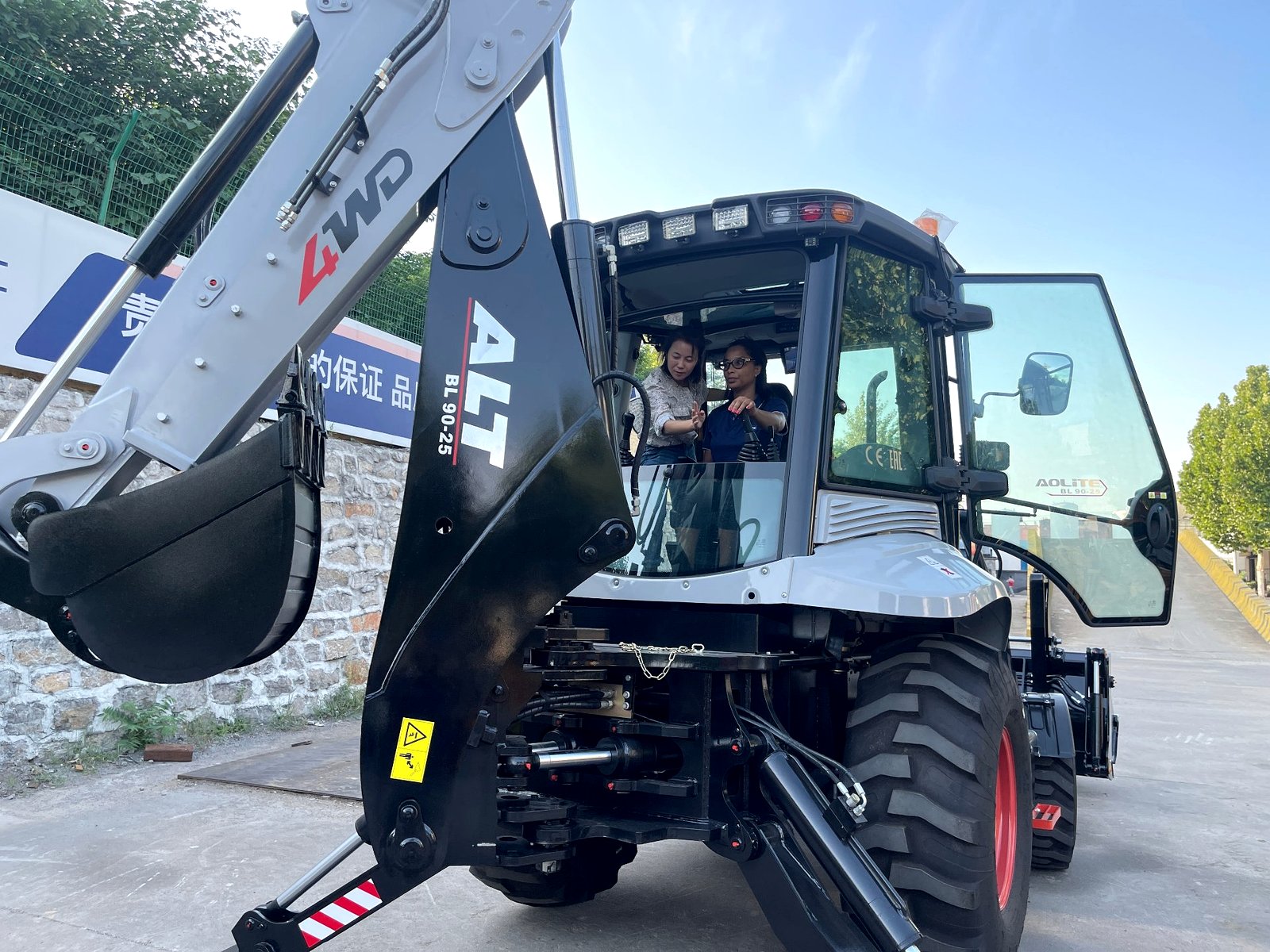 Vivian explaining the cab controls to the client — backhoe loader