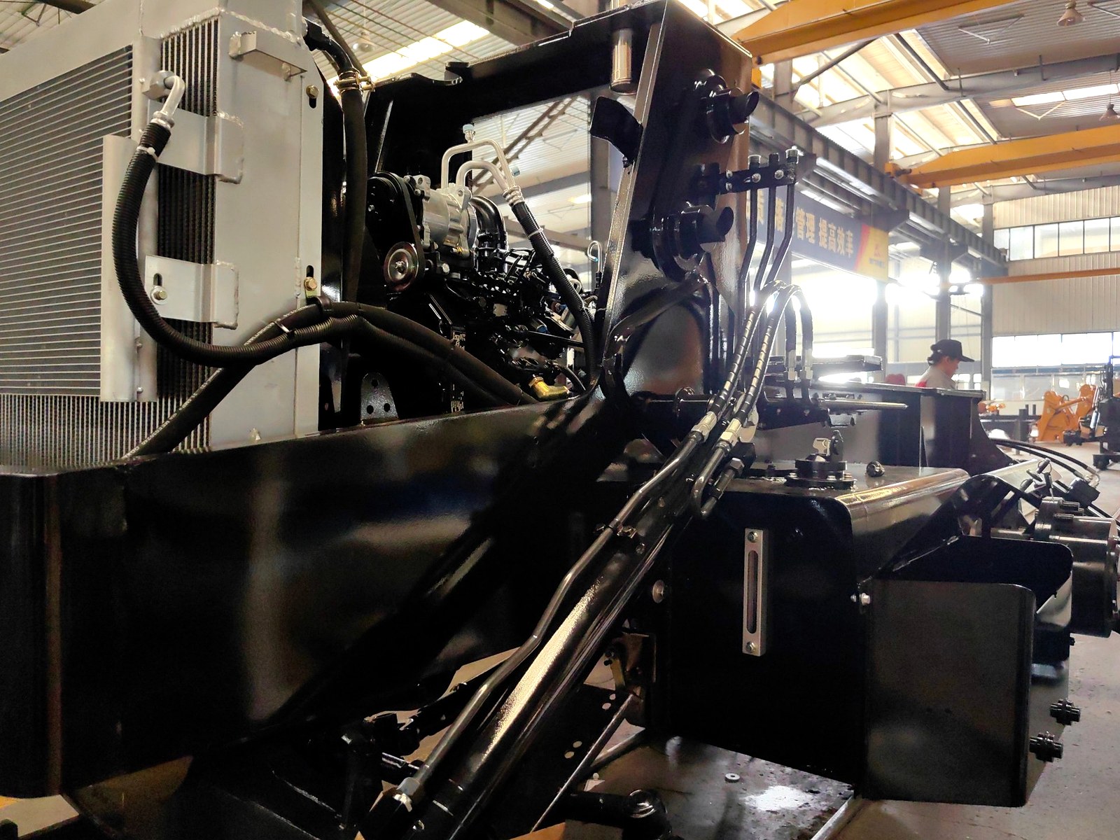 Engine compartment and hydraulic hoses under inspection — backhoe loader